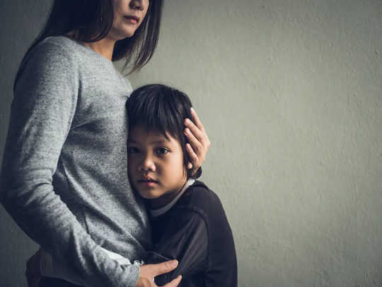 A woman hugs a boy who has his hands around her waist