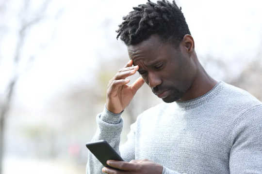 Man looking at his phone with a confused look on his face