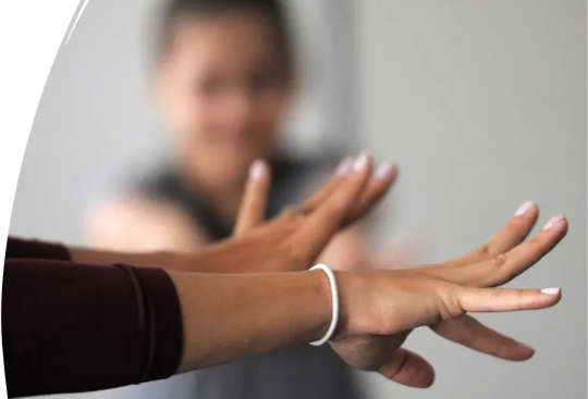 With outstretched arms, neuroscientist Lana Ruvolo Grasser performs a tension-and-release exercise with her study participants.