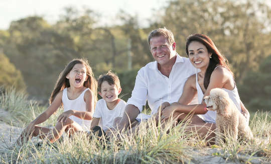 a joyful family sitting together outside in an meadow