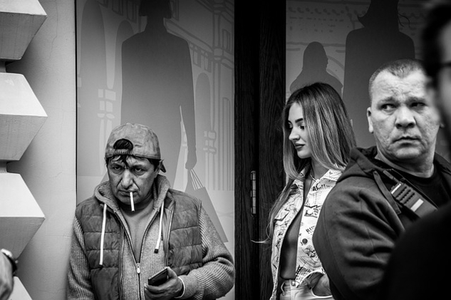 man smoking a cigarette with two people looking at him