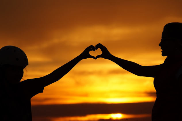 a woman anc child creating a heart shape with their hands touching