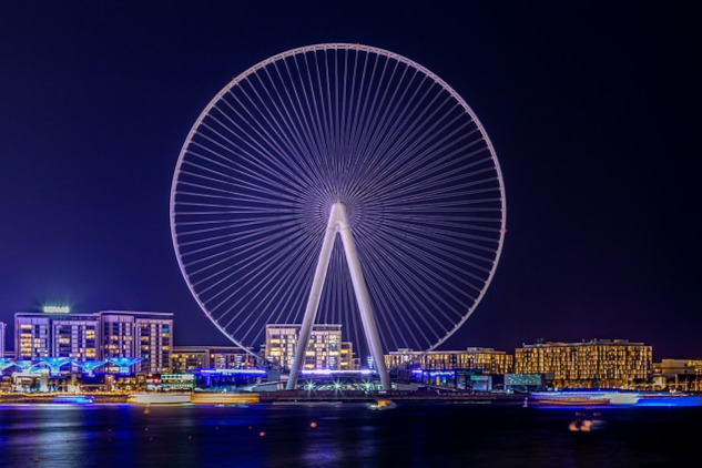 a gigantic ferris wheel overlookinga cityscape