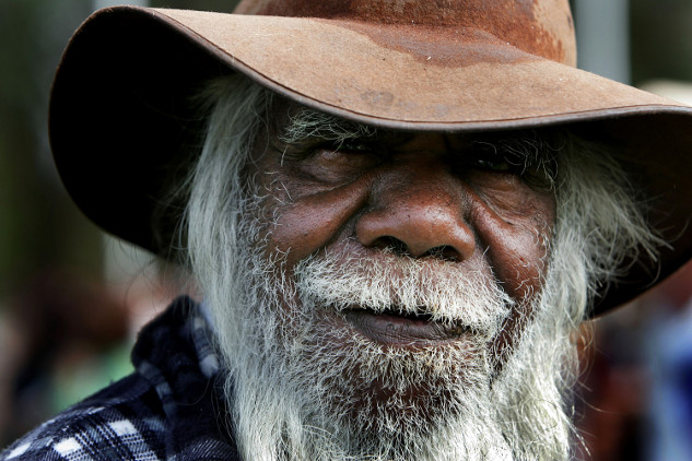 Indigenous elder teaching about traditional ecological knowledge with a backdrop of nature and climate-related imagery.