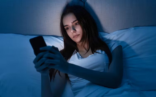 Close-up of a person using a smartphone at night, highlighting concerns about blue light exposure and its potential effects on skin health