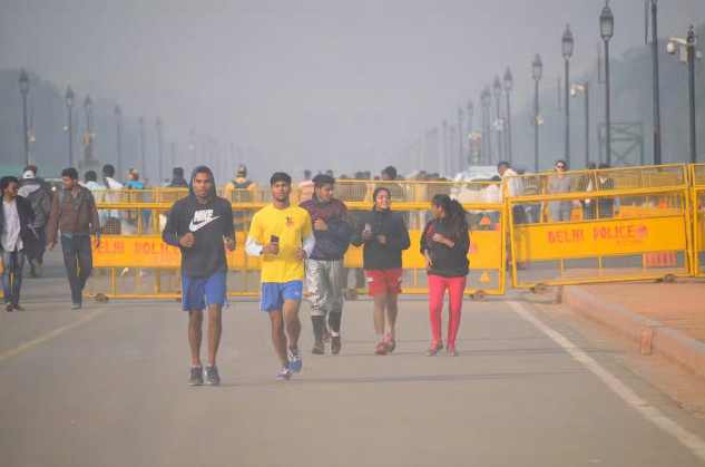 Men running through smog in Delhi, highlighting the impact of air pollution on athletes' health and performance.