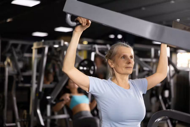 Woman uses weights at the gym to build strength and prevent muscle loss.