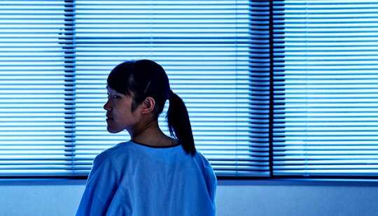 A young woman by herself in a hospital room