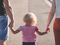 a child holding hands with her parents - one on each side