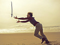 a man on a beach playing with a sword