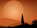 a monk standing peaceful in front of the setting sun