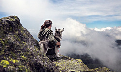 woman sitting outside with her arm around a husky dog