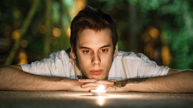 a young man laying down staring into a candle flame