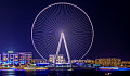 a gigantic ferris wheel overlookinga cityscape