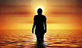 woman standing in the ocean looking at the rising sun