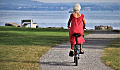 a senior woman with white hair and a red dress riding a bicycle