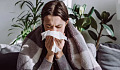 A person sitting indoors with natural light, surrounded by plants, emphasizing the positive impact of the indoor microbiome on health.