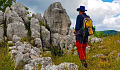 a man with a backpack standing in front of rocks and boulders