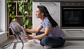 A young woman sitting close to a large electric fan. Not the most effective way to cool down