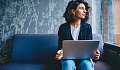 woman sitting in front of a laptop looking off into the distance