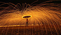 man holding an umbrella protecting him from sparks from a fire