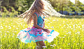 young girl dancing and twirling outside in a meadow