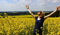 women standing in a field of flowers, smiling with her hands open up to the sky