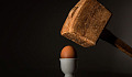 an egg under the aim of a hammer