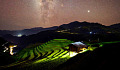 bright light from under small building light terraced rice fields under starry sky