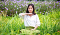 a woman sitting with eyes closed in a meadow