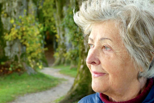 an older woman standing outside looking at something in the distance