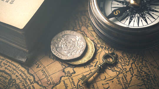 photo of a key, a compass, coins, overlayed on an old map