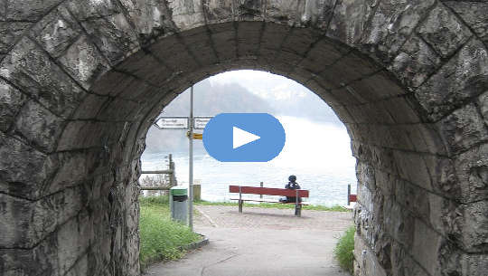 person sitting on a bench at the end of a tunnel with signposts pointing left or right