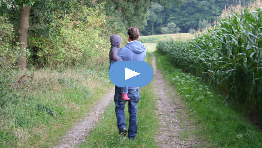 father holding son in his arms and walking down the road