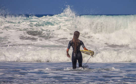 surfer with tiny surfboard facing huge waves