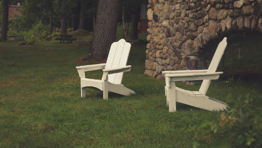 two empty lawn chairs in from of a rock wall