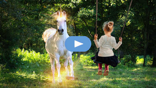 young girl on a swing looking at a unicorn