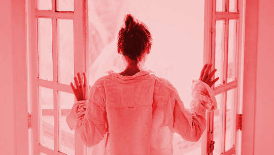 woman looking out open patio doors