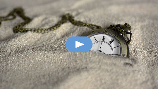 a pocket watch semi-buried in the sand