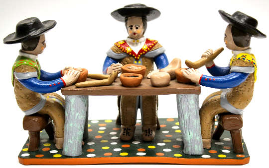 clay figurines sitting at a table eating food made of clay