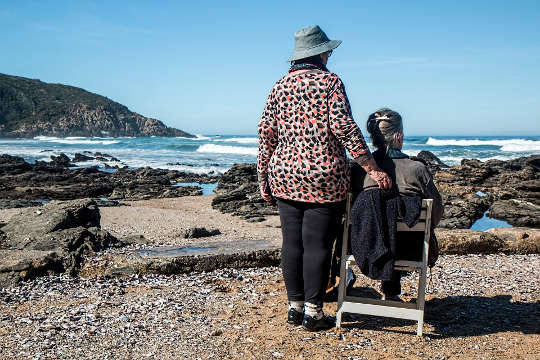 two women, one sitting, one standing, looking out at the ocean