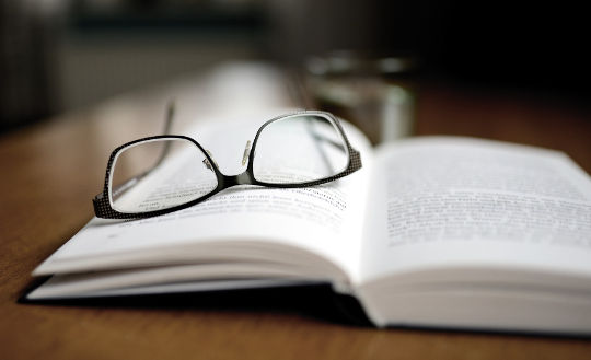 an open book with a pair of glasses laying on it