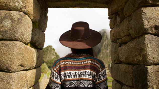 Indian woman standing under a stone arch in Machu Picchu