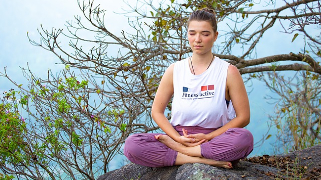 young woman sitting outside in a meditation position