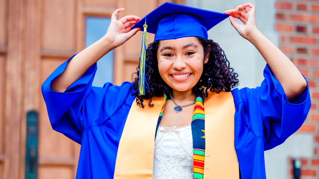 a young woman proudly wearaing a blue graduation cap and gown