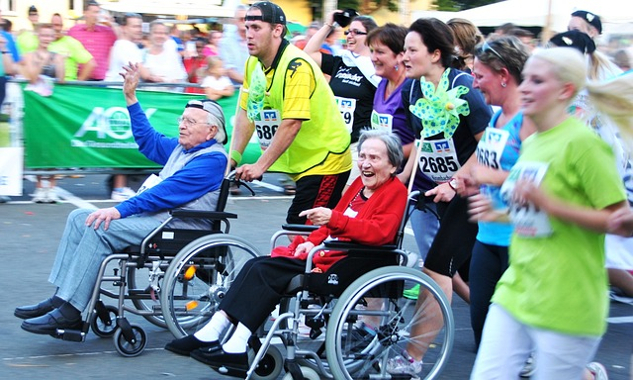 people in wheelchairs with someone standing behind their chair