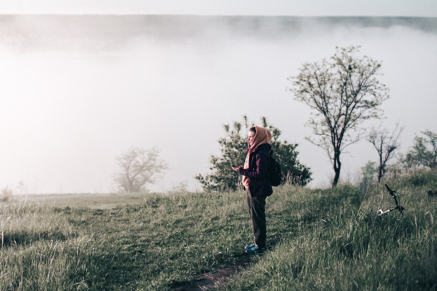 a woman wearing a scarf standing on a hillside