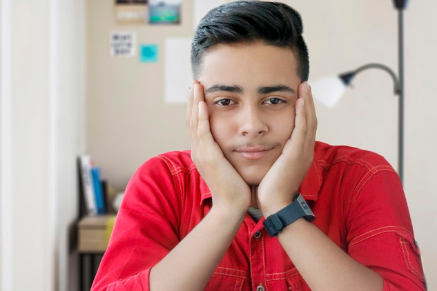 young man with his chin resting on his hands smiling peacefully