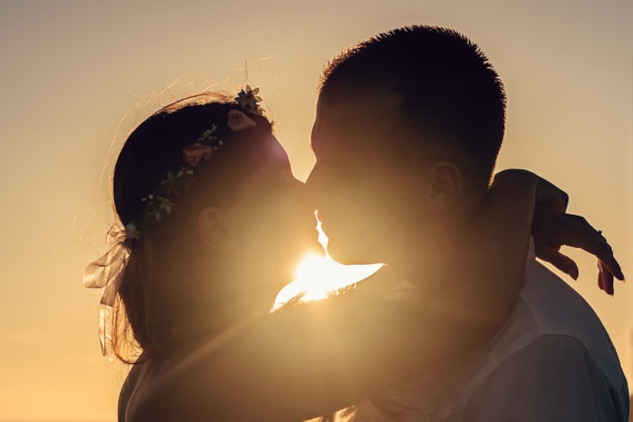 two people kissing with the light shining brightly behind them