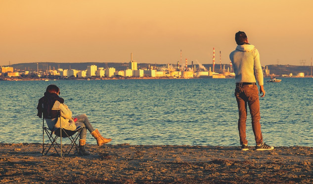 two people igoring each other... one sitting the other standing some distance away